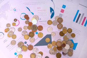 経済資料の上に置かれた各国のコイン（インフレ・経済）